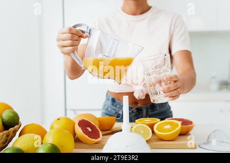 Closeup of woman pouring freshly squeezed homemade orange juice into the glass Stock Photo