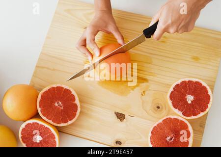 Young woman cutting grapefruits on cutting board for homemade fresh juice Stock Photo