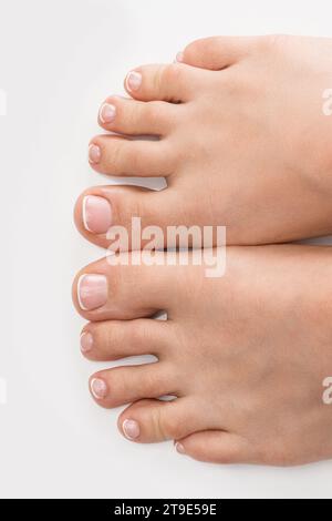 Closeup of female feet with soft skin and french pedicure on white background Stock Photo