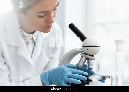 Woman student is using microscope in a laboratory during science research work Stock Photo