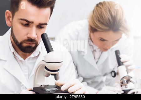 Two students are working in a laboratory using microscopes during science research work Stock Photo