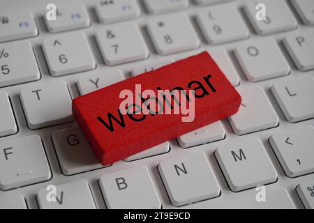 Closeup image of wooden block with text WEBINAR on top of computer keyboard. Stock Photo