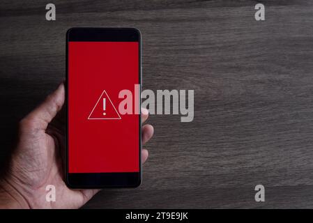 Smartphone with triangle caution warning icon. Copy space for text. System error, malware and cyber crime concept. Stock Photo