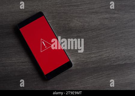 Smartphone with triangle caution warning icon. Copy space for text. System error, malware and cyber crime concept. Stock Photo