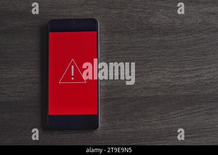 Smartphone with triangle caution warning icon. Copy space for text. System error, malware and cyber crime concept. Stock Photo