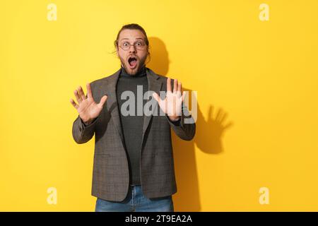 Young surprised man wearing glasses against yellow background Stock Photo