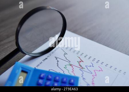 Closeup image of calculator, magnifying glass and line graph. Data and finance analysis, business intelligence and trends concept. Stock Photo