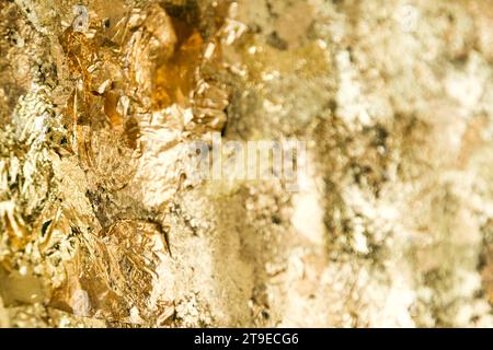 Abstract closeup shot of a uneven surface covered with exfoliated crumpled gold foil. Stock Photo
