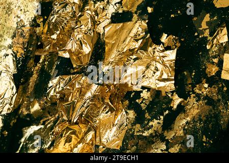 Abstract closeup shot of a uneven surface covered with exfoliated crumpled gold foil. Stock Photo