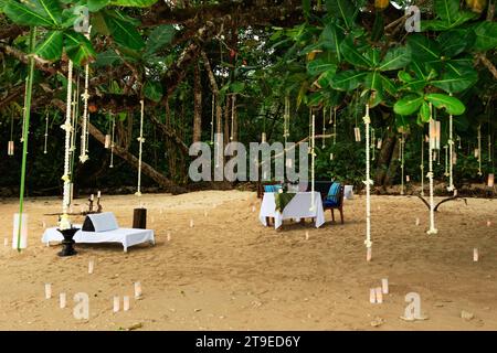 Dining table set up for a romantic date on a sandy beach, surrounded by candles. Stock Photo