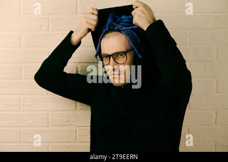 The Vibrant Man with Striking Purple Dreadlocks and Unique Style, puts on a hood. Stock Photo