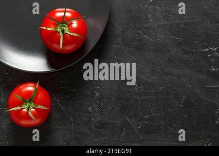 Tomatoes two pieces, on gray plate and dark background, top view. Stock Photo