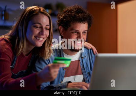 Young couple doing online shopping from home using a laptop and a credit card. Stock Photo