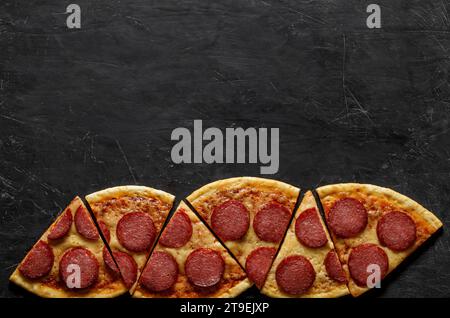 Pizza pepperoni Italian cooked, six cutting pieces, top view dark background, below, with space to copy text. Stock Photo