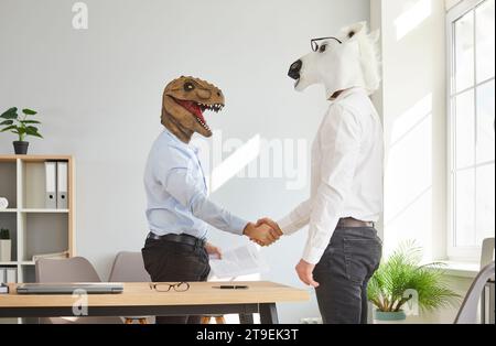 Two colleagues in animal head masks handshaking after meeting Stock Photo