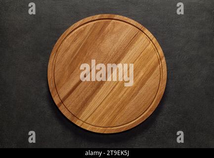 Round cutting board wooden for pizza, empty, in middle top view dark background, with space to copy text. Stock Photo