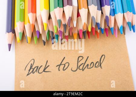 Color pencils and back to school title on a notebook Stock Photo