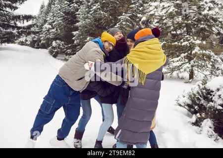 Company of cheerful young friends happily embraces during meeting before winter walk. Stock Photo