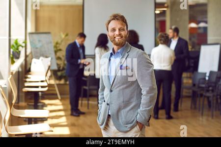 Happy confident bearded business man looking at the camera and smiling in the office. Stock Photo