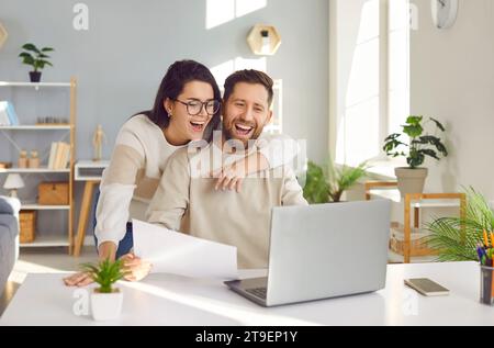 Happy young family couple using their laptop computer and paying their bills online Stock Photo