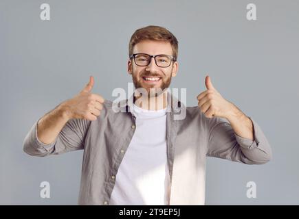 Portrait of happy male teacher or student in eyeglasses giving thumbs up and smiling Stock Photo
