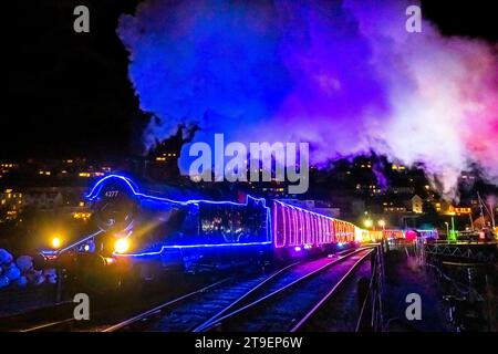 Kingswear, Devon, UK.  24th November 2023.   The Christmas Train of Lights on the Dartmouth Steam Railway which runs between 24th November to 30th December 2023, pulls out of Kingswear station in Devon on its way to Paignton.  The carriages and steam locomotives on the festive service are lit inside and out with coloured lights.  Picture Credit: Graham Hunt/Alamy Live News Stock Photo