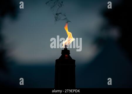 flame burning orange from a single candle torch light during night time Stock Photo