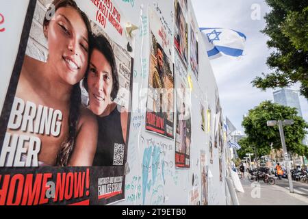 Tel Aviv, Israel. 22nd Nov, 2023. Posters featuring photographs of hostages held by Hamas seen taped on a wall with a flying Israeli flag in Tel Aviv. As the Israeli-Palestinian conflict continues, 13 Israeli hostages have been released on the 24 November from Gaza stripe. About 240 hostages have been held by Hamas in Gaza since the attack on Israel on 7th October. Credit: SOPA Images Limited/Alamy Live News Stock Photo