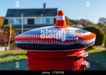 Poole, Dorset, UK. 25th November, 2023. A knitted crocheted postbox topper under construction triangular sign with traffic cone  adds a humorous touch on a cold frosty morning, as a holder between the last Remembrance topper and the next one. Residents wait with excited anticipation for the arrival of the Christmas themed postbox topper - whilst waiting, the holding theme brings a smile to the face! Credit: Carolyn Jenkins/Alamy Live News Stock Photo