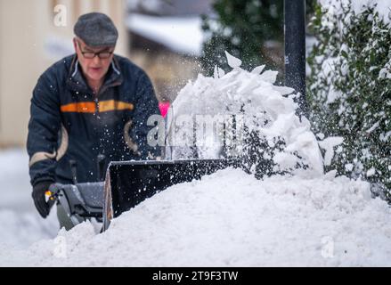 Oberwiesenthal, Germany. 25th Nov, 2023. A man clears the sidewalk with a snow blower. There was fresh snow in the Erzgebirge during the night. Credit: Kristin Schmidt/dpa/Alamy Live News Stock Photo