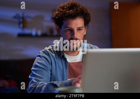 Caucasian man using laptop at home working late at night concentrated. Stock Photo