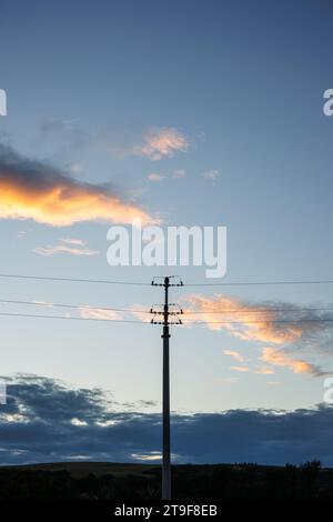 Low voltage power pole against sunset sky. Electricity and environment Stock Photo