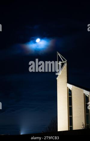 Corona around the moon above the tower of a modern church at night. Stock Photo