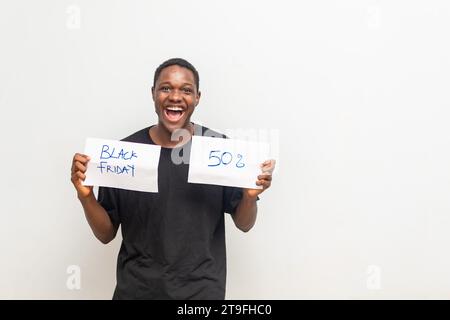 Cheerful african man holding cards with Black Friday inscription, announcing huge discount. Stock Photo