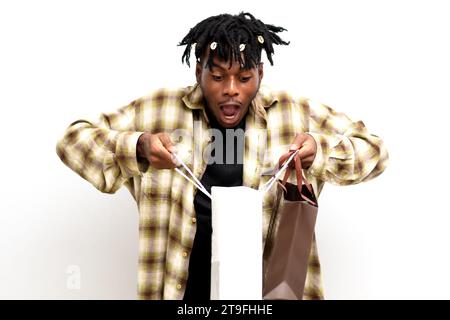 Photo of a Shocked young black African man on dreadlocks with shopping bags isolated on white background. Black Friday sale Stock Photo