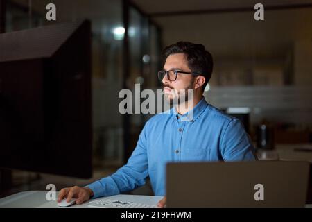 Busy young business man programmer using computer working late in office. Stock Photo