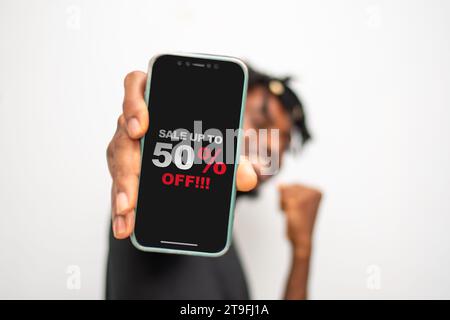 Design sale 50% discount. Man hand holding smartphone with discount offer message on the screen, black background sale poster template. Stock Photo