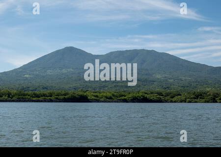 Coastline Seen From Afar with a Volcanic Mountain, Lush Vegetation Forest, Beach, and Houses with a Calm Ocean Stock Photo