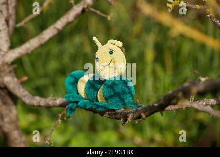 Knitted toy caterpillar on a tree in the garden Stock Photo