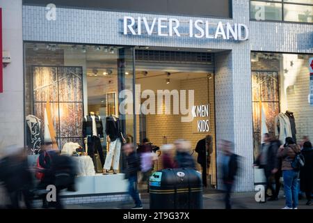 LONDON- NOVEMBER 23, 2023: River Island store and motion blurred shoppers on Oxford Street, landmark retail destination Stock Photo