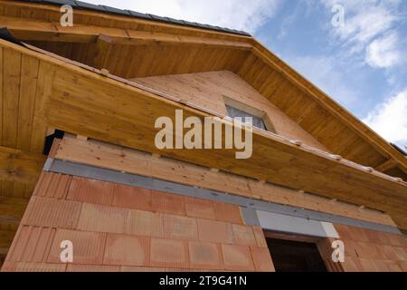 Construction of unfinished house made of bricks, wood and timber.  Building site and blue sky in background. Home building. Stock Photo