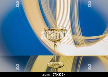 Close-up of martini glass with ice against blue-white abstract backdrop. Stock Photo