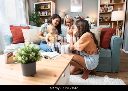 Happy family. Grandmother, mother, aunt and little baby having fun at home. Relatives visiting new born child. Stock Photo