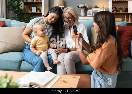 Happy family. Grandmother, mother, aunt and little baby having fun at home. Relatives visiting new born child. Stock Photo