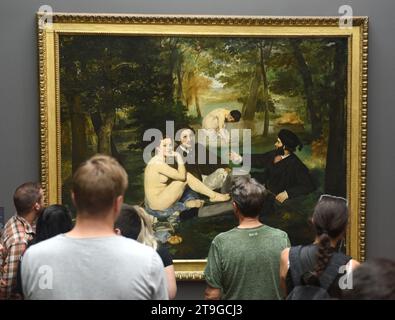 Paris, France - August 29, 2019: Visitor near the Le dejeuner sur l'herbe by Edouard Manet painting in Museum d'Orsay in Paris, France. Stock Photo
