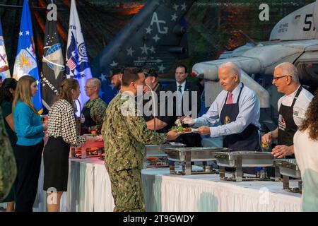 Norfork, United States of America. 19 November, 2023. U.S. President Joe Biden, left, and celebrity chef Robert Irvine serve Thanksgiving meals to members of the armed forces and their families during a Friendsgiving dinner at Naval Station Norfolk, November 19, 2023 in Washington, D.C. The meal was hosted by celebrity chef Robert Irvine Credit: MC2 Anderson Branch/US Navy Photo/Alamy Live News Stock Photo