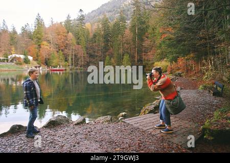 Young happy woman taking picture of preteen kid by mountain lake, family travel with children Stock Photo