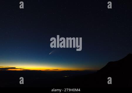 Comet NEOWISE sets in a richly colored and star spangled western sky over Death Valley and Badwater Basin as seen from Dante’s View. Stock Photo