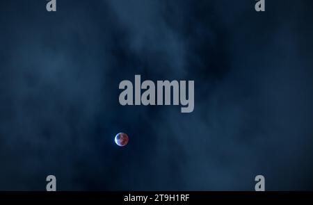 Partial lunar eclipse, a blood moon, in a blue-black sky. November 2021. Stock Photo
