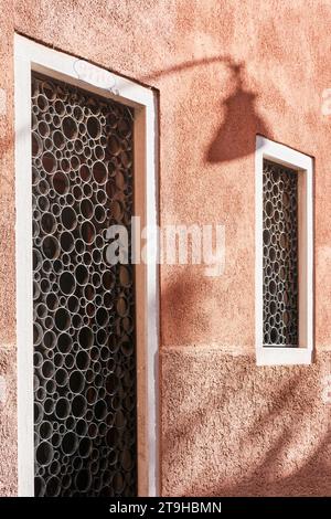 Venice, Italy - November 9 2023: Architectural detail of a circular wrought iron ornaments on window and door openings with pink wall Stock Photo